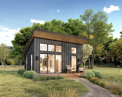 A modern single-story cabin with dark charcoal vertical siding, large wood-look overhangs, and expansive glass windows, shown on a landscaped lawn with trees and a blue sky.