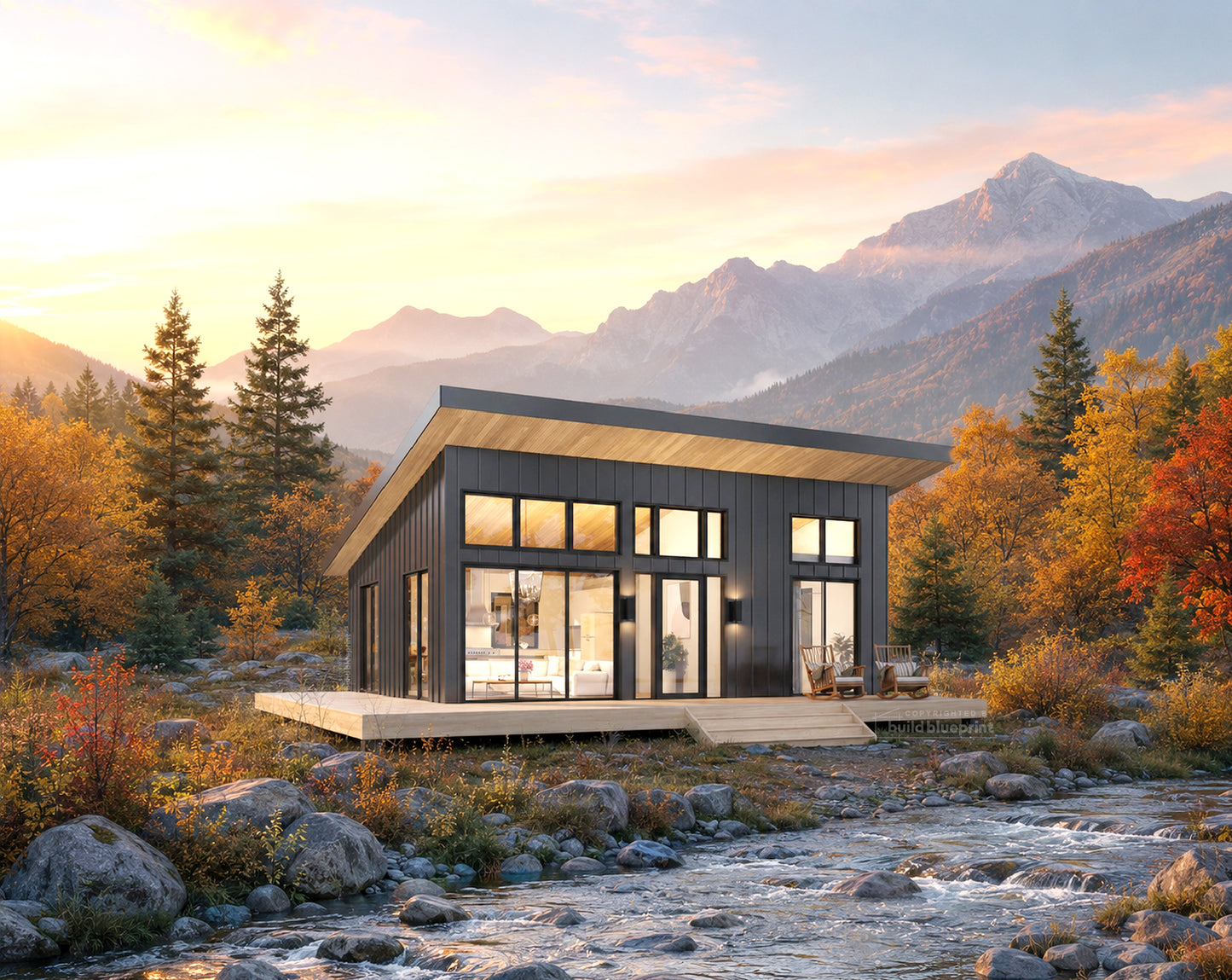 Modern minimalist cabin with dark wood siding and large glass windows, situated on a wooden deck beside a rocky stream with autumn trees and mountains in the background.