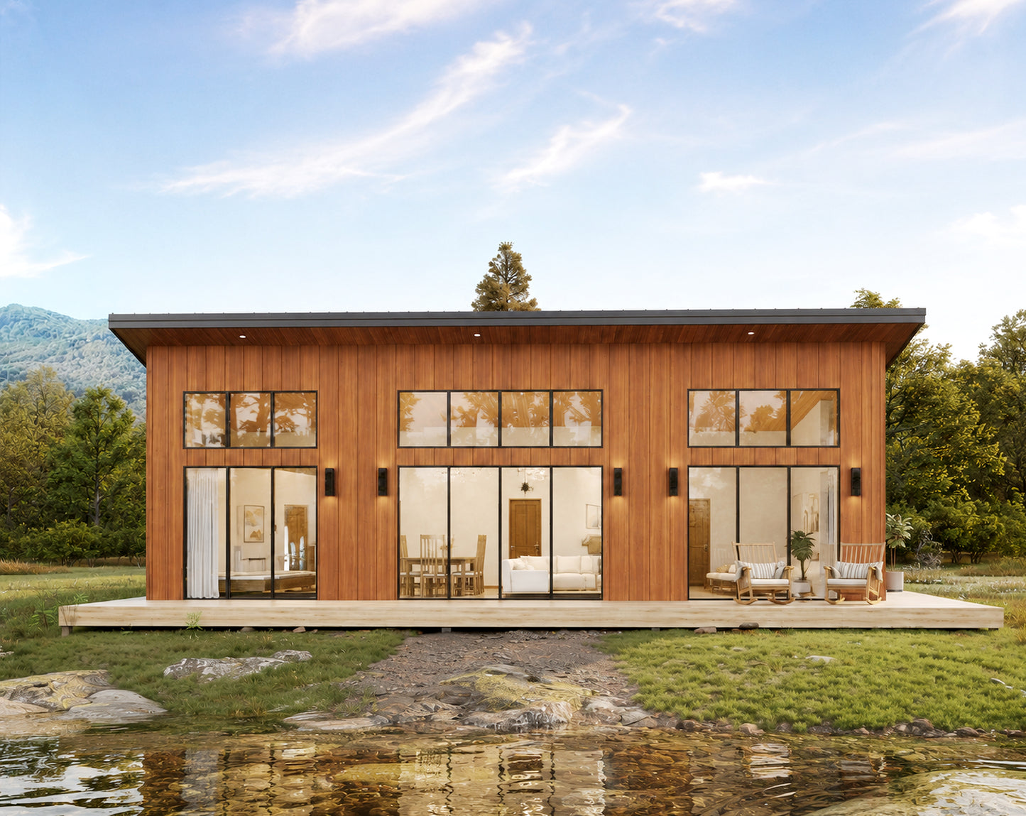 A modern single-story cabin with warm wood siding and large floor-to-ceiling glass windows, shown on a landscaped lot with grass, trees, mountains, and a small pond in the foreground.