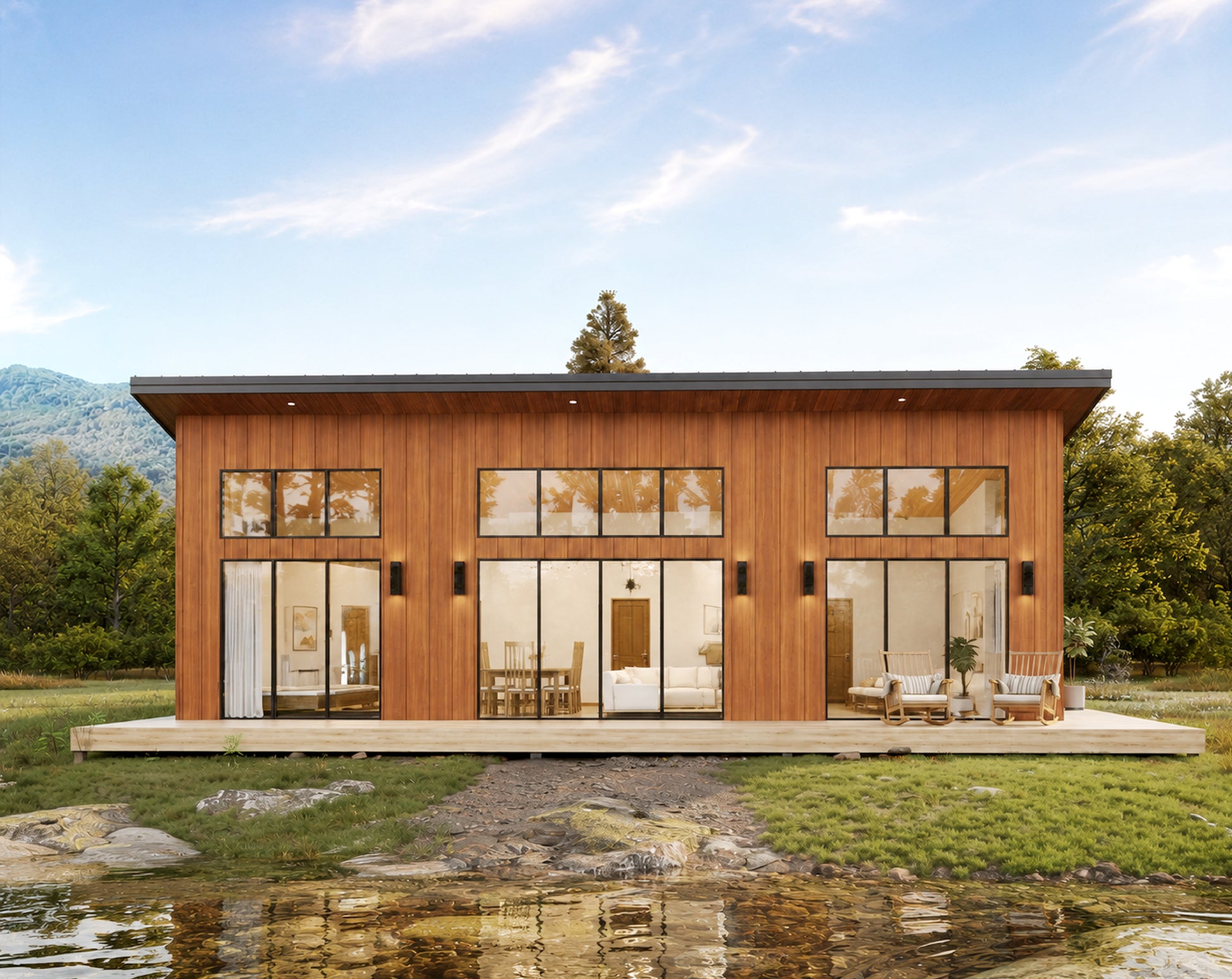 A modern single-story cabin with warm wood siding and large floor-to-ceiling glass windows, shown on a landscaped lot with grass, trees, mountains, and a small pond in the foreground.