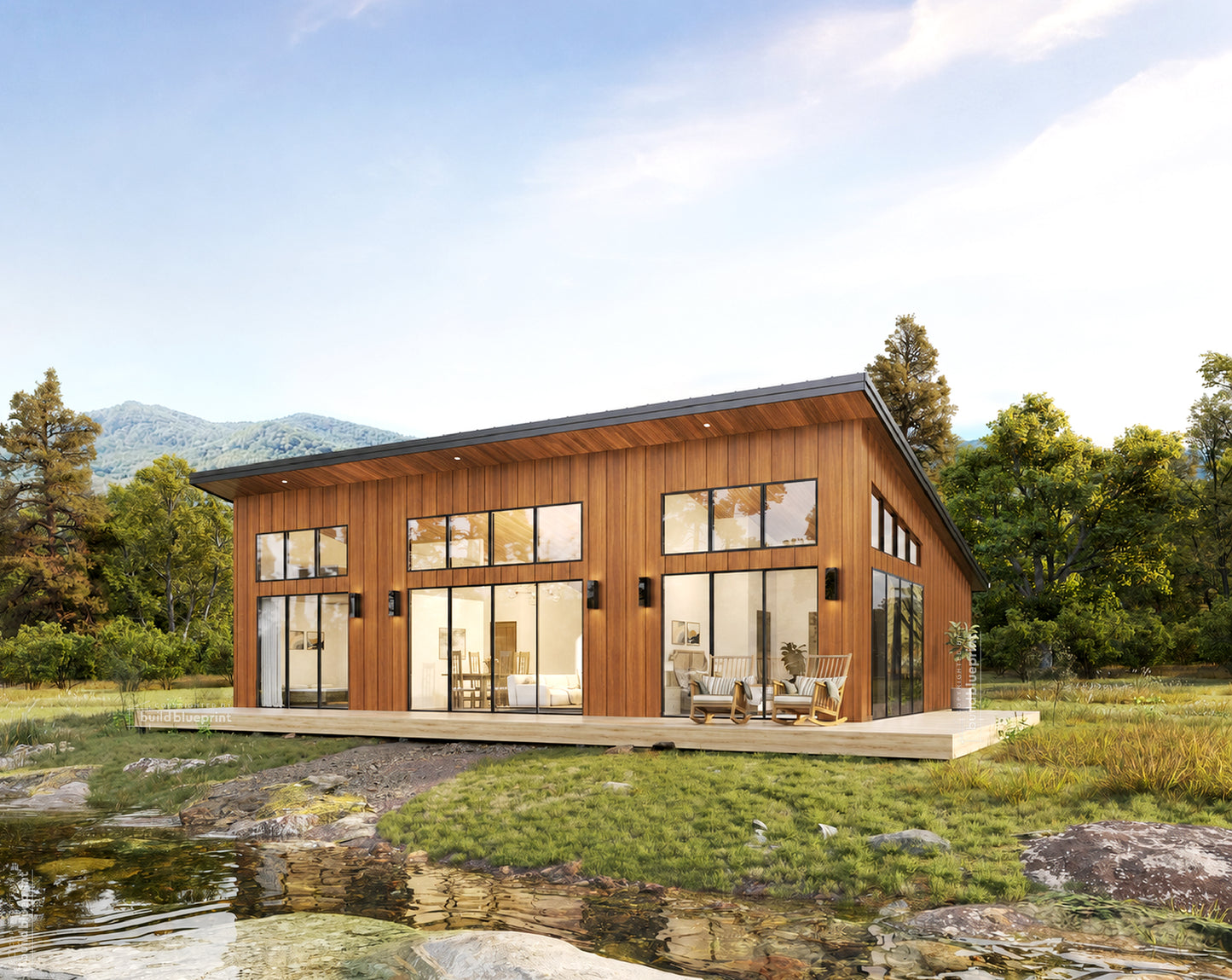 A modern single-story house with warm wood siding and large glass windows, situated on a grassy bank beside a shallow stream with rocks and trees in the background.