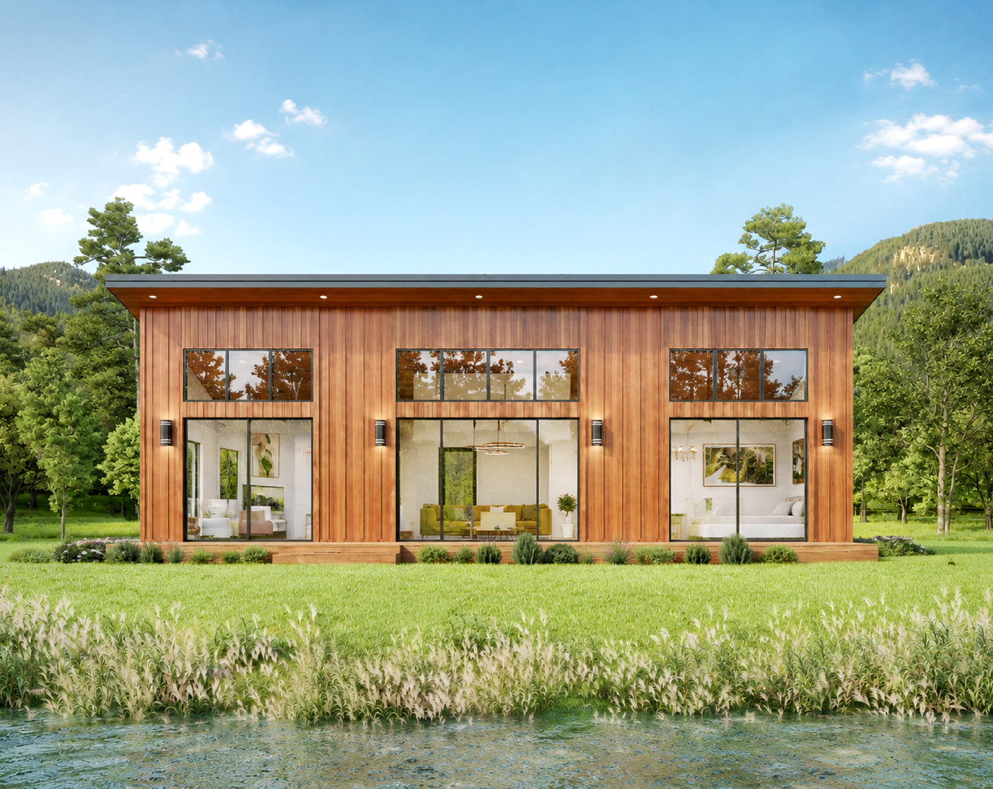 A modern single-story cabin with dark charcoal gray vertical siding, large floor-to-ceiling windows, and warm wood trim, situated on a grassy bank beside a clear stream with trees and mountains in the background.